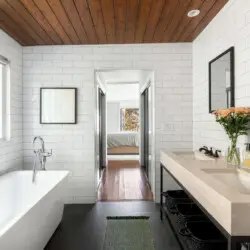 Bathroom with large bathtub, white tiles, and wooden ceiling at Sun-Drenched Spanish Manor in Mar Vista - by Open Air Homes.