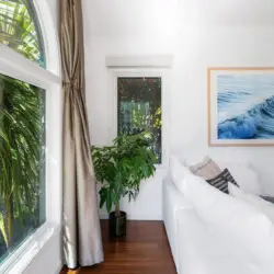 Living room with white sofa, decorative pillows, and large window at Sun-Drenched Spanish Manor in Mar Vista - by Open Air Homes.