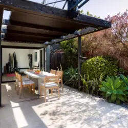 Outdoor dining area with table and chairs under a pergola at Sun-Drenched Spanish Manor in Mar Vista - by Open Air Homes.