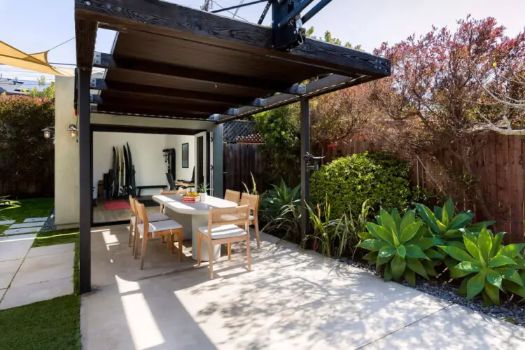 Outdoor dining area with table and chairs under a pergola at Sun-Drenched Spanish Manor in Mar Vista - by Open Air Homes.