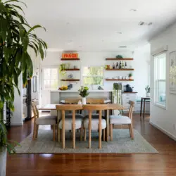 Dining area with wooden table and chairs, view of kitchen at Sun-Drenched Spanish Manor in Mar Vista - by Open Air Homes.