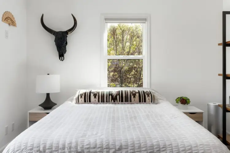 Bedroom with bed, bedside table, lamp, and window at Sun-Drenched Spanish Manor in Mar Vista - by Open Air Homes.