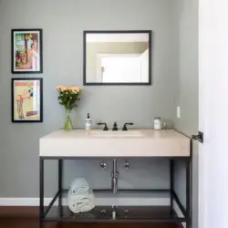 Bathroom vanity with sink, mirror, framed artwork, and vase at Sun-Drenched Spanish Manor in Mar Vista - by Open Air Homes.