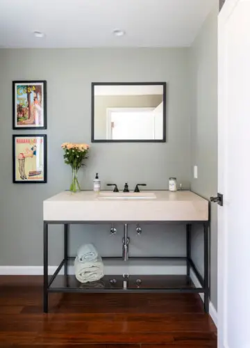 Bathroom vanity with sink, mirror, framed artwork, and vase at Sun-Drenched Spanish Manor in Mar Vista - by Open Air Homes.