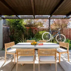 Outdoor dining area with table and chairs under a pergola at Sun-Drenched Spanish Manor in Mar Vista - by Open Air Homes.