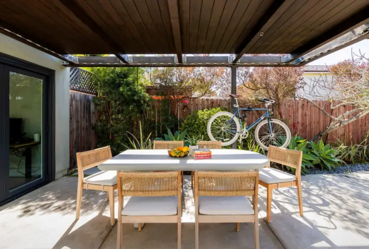 Outdoor dining area with table and chairs under a pergola at Sun-Drenched Spanish Manor in Mar Vista - by Open Air Homes.