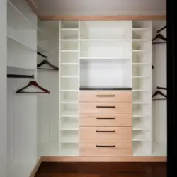 Walk-in closet with white shelves and wooden drawers at Sun-Drenched Spanish Manor in Mar Vista - by Open Air Homes.