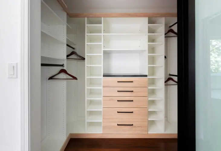 Walk-in closet with white shelves and wooden drawers at Sun-Drenched Spanish Manor in Mar Vista - by Open Air Homes.