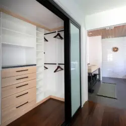 Walk-in closet with white shelves and wooden drawers at Sun-Drenched Spanish Manor in Mar Vista - by Open Air Homes.