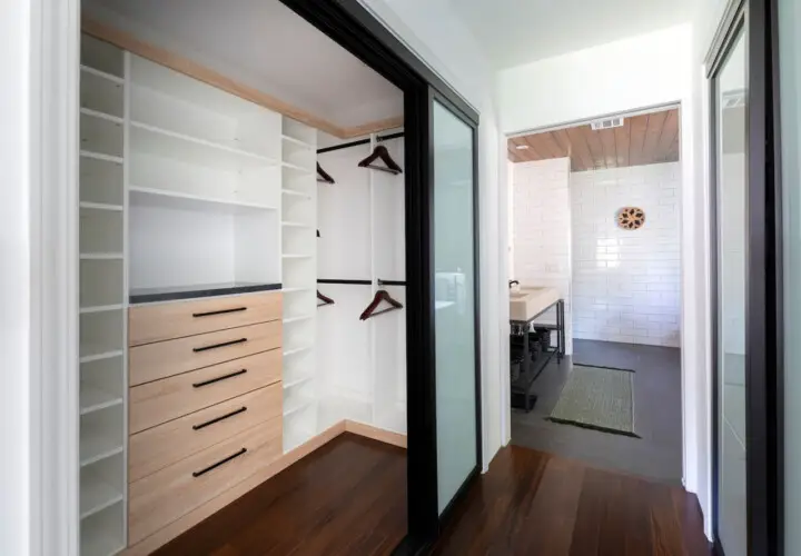 Walk-in closet with white shelves and wooden drawers at Sun-Drenched Spanish Manor in Mar Vista - by Open Air Homes.