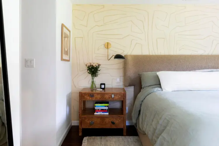 Bedroom with bed, wooden nightstand, and decorative wall design at Sun-Drenched Spanish Manor in Mar Vista - by Open Air Homes.