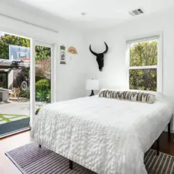 Bedroom with bed, bedside table, and sliding glass door to patio at Sun-Drenched Spanish Manor in Mar Vista - by Open Air Homes.