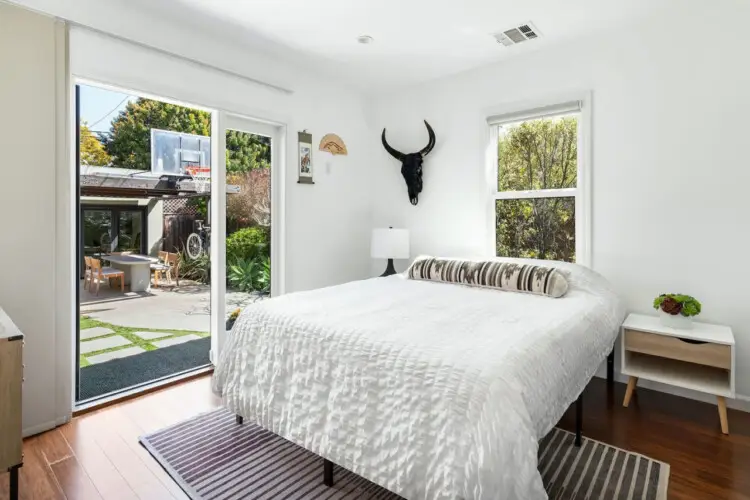 Bedroom with bed, bedside table, and sliding glass door to patio at Sun-Drenched Spanish Manor in Mar Vista - by Open Air Homes.