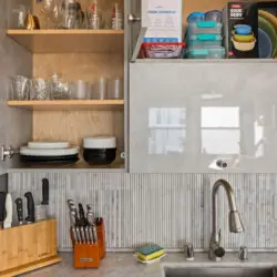 Kitchen cabinets with dishes and utensils at Skyline View Loft with Chef's Kitchen: DTLA - by Open Air Homes.