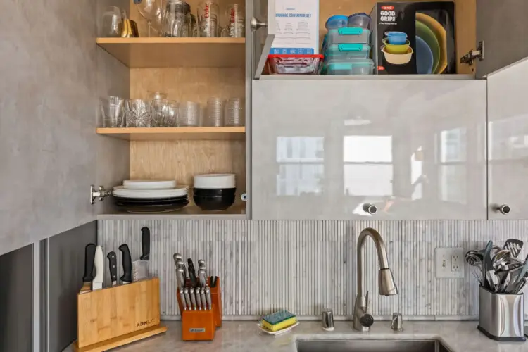 Kitchen cabinets with dishes and utensils at Skyline View Loft with Chef's Kitchen: DTLA - by Open Air Homes.