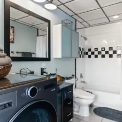 Laundry area within a bathroom, featuring a washing machine and a basket of towels