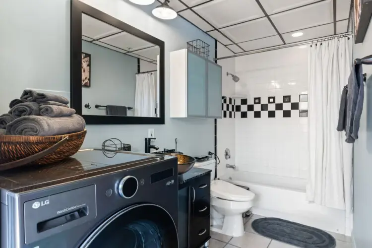 Laundry area within a bathroom, featuring a washing machine and a basket of towels