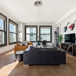 Living room with large windows, leather sofa, and TV at Skyline View Loft with Chef's Kitchen: DTLA - by Open Air Homes.