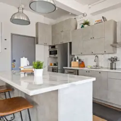 Modern kitchen with marble countertop, chairs, and stainless steel appliances at Skyline View Loft with Chef's Kitchen: DTLA - by Open Air Homes.