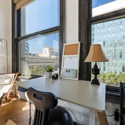 Workspace with desk, chair, and large windows providing city views at Skyline View Loft with Chef's Kitchen: DTLA - by Open Air Homes.