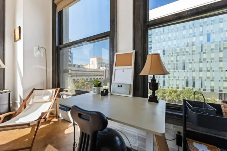 Workspace with desk, chair, and large windows providing city views at Skyline View Loft with Chef's Kitchen: DTLA - by Open Air Homes.