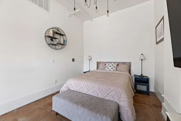 Bedroom with bed, pillows, and bench at Skyline View Loft with Chef's Kitchen: DTLA - by Open Air Homes.