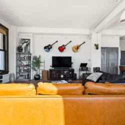 Living room with large windows, leather sofa, and TV at Skyline View Loft with Chef's Kitchen: DTLA - by Open Air Homes.