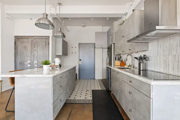 Modern kitchen with central island, pendant lighting, and wine cooler at Skyline View Loft with Chef's Kitchen: DTLA - by Open Air Homes.