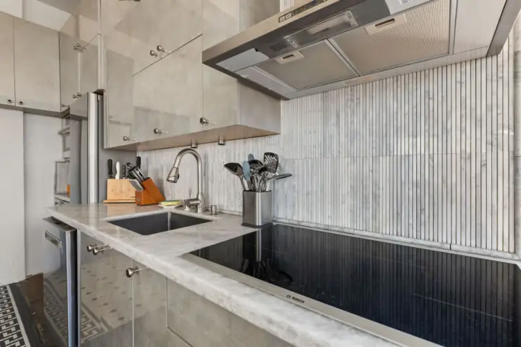 Modern kitchen sink and counter at Skyline View Loft with Chef's Kitchen: DTLA - by Open Air Homes.