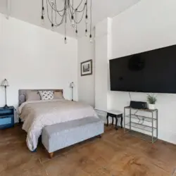 Comfortable bedroom with a bed, side tables, TV, and decorative elements at Skyline View Loft with Chef's Kitchen: DTLA - by Open Air Homes.