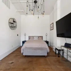 Bedroom with a bed, TV, and minimalist design at Skyline View Loft with Chef's Kitchen: DTLA - by Open Air Homes.