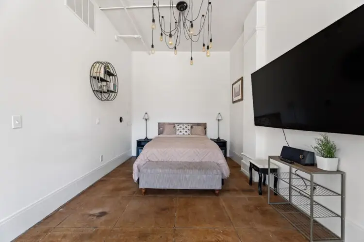 Bedroom with a bed, TV, and minimalist design at Skyline View Loft with Chef's Kitchen: DTLA - by Open Air Homes.