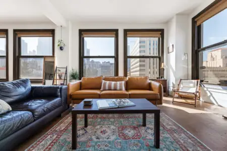 Living room with sofa, coffee table, and large windows offering city views at Skyline View Loft with Chef's Kitchen: DTLA - by Open Air Homes.