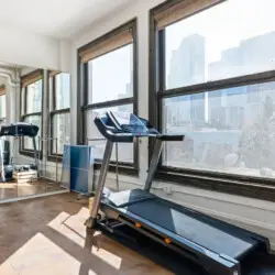 Fitness area with a treadmill and large windows offering city views at Skyline View Loft with Chef's Kitchen: DTLA - by Open Air Homes.