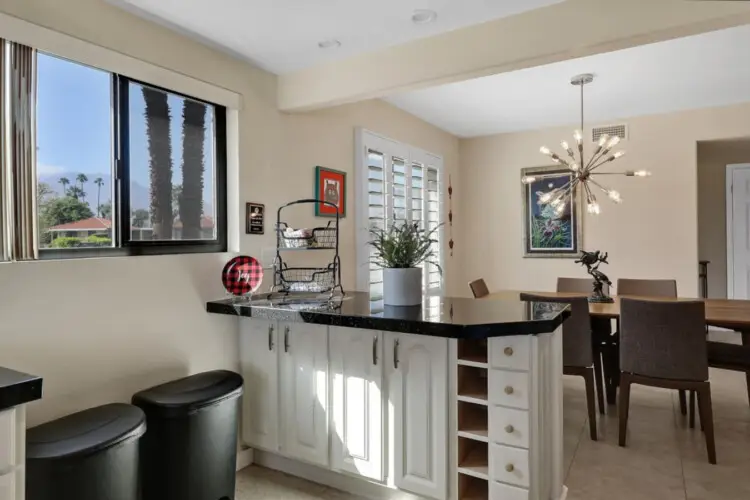 Dining room with table and chairs, and kitchen counter with cabinets at Sunrise Serenity: Panoramic Views & Resort Living - by Open Air Homes