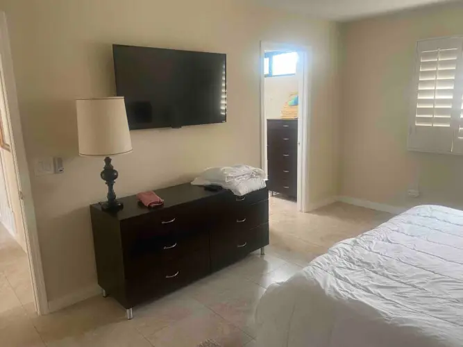 Bedroom with bed, dresser, lamp, and wall-mounted TV at Sunrise Serenity: Panoramic Views & Resort Living - by Open Air Homes