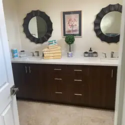 Bathroom with double vanity, two mirrors, and decorative plant at Sunrise Serenity: Panoramic Views & Resort Living - by Open Air Homes