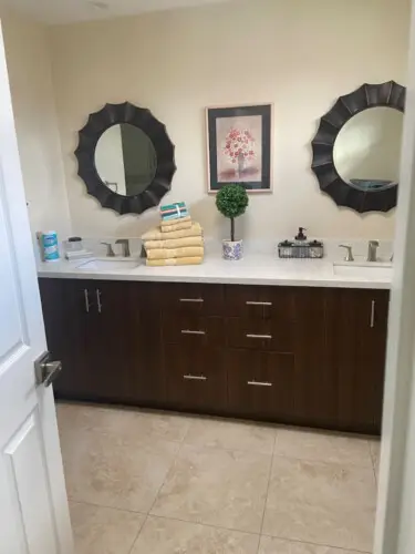 Bathroom with double vanity, two mirrors, and decorative plant at Sunrise Serenity: Panoramic Views & Resort Living - by Open Air Homes