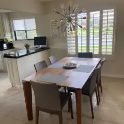 Dining area with wooden table, gray chairs, and modern light fixture at Sunrise Serenity: Panoramic Views & Resort Living - by Open Air Homes