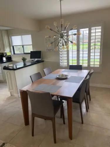 Dining area with wooden table, gray chairs, and modern light fixture at Sunrise Serenity: Panoramic Views & Resort Living - by Open Air Homes