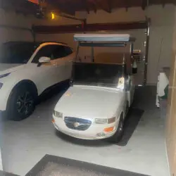 Garage with car and golf cart at Sunrise Serenity: Panoramic Views & Resort Living - by Open Air Homes