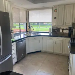 Kitchen with white cabinetry, stainless steel appliances, and large windows at Sunrise Serenity: Panoramic Views & Resort Living - by Open Air Homes