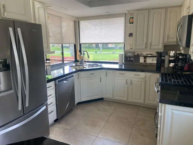 Kitchen with white cabinetry, stainless steel appliances, and large windows at Sunrise Serenity: Panoramic Views & Resort Living - by Open Air Homes