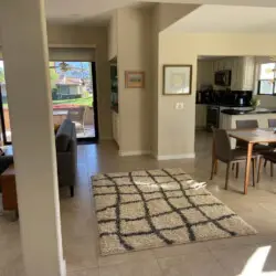 Dining area with table and chairs, and living area in the background at Sunrise Serenity: Panoramic Views & Resort Living - by Open Air Homes