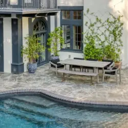 Exterior view of Laurel Canyon Classic Hollywood Residence W/ Pool with stone patio, dining table, chairs, and pool by Open Air Homes.