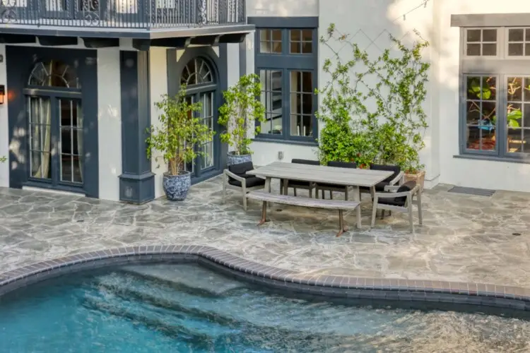 Exterior view of Laurel Canyon Classic Hollywood Residence W/ Pool with stone patio, dining table, chairs, and pool by Open Air Homes.