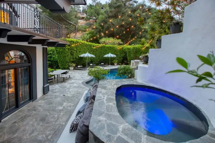 Pool and spa area with stone deck and outdoor seating at Laurel Canyon Classic Hollywood Residence W/ Pool by Open Air Homes.