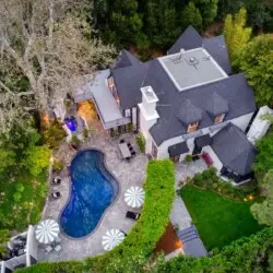 Aerial view of Laurel Canyon Classic Hollywood Residence W/ Pool with stone patio, lounge chairs, umbrellas, and swimming pool surrounded by greenery by Open Air Homes.