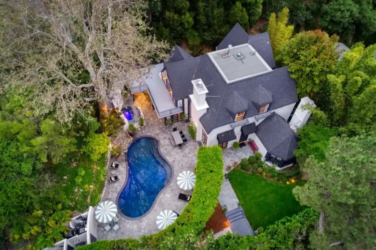 Aerial view of Laurel Canyon Classic Hollywood Residence W/ Pool with stone patio, lounge chairs, umbrellas, and swimming pool surrounded by greenery by Open Air Homes.