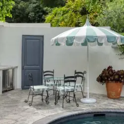 Outdoor seating area with table, chairs, and umbrella next to a pool at Laurel Canyon Classic Hollywood Residence W/ Pool by Open Air Homes.